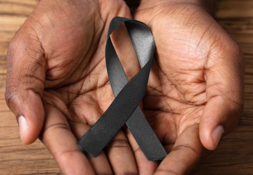 Hands cupped together holding a black ribbon for skin cancer awareness